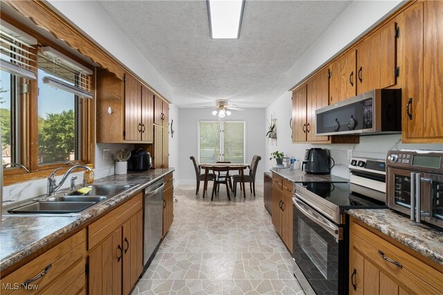 2715 Eastwood Dr, Wooster, OH 44691 - kitchen featuring stainless steel appliances, a textured ceiling, brown cabinets, a ceiling fan, and light stone finish flooring