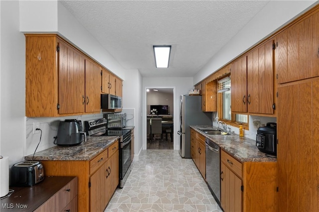 2715 Eastwood Dr, Wooster, OH 44691 - kitchen with appliances with stainless steel finishes, dark countertops, light stone finish flooring, brown cabinetry, and a textured ceiling