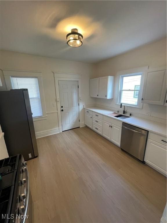 3363 E 125th St, Cleveland, OH 44120 - kitchen with appliances with stainless steel finishes, light wood-style floors, white cabinets, and light countertops