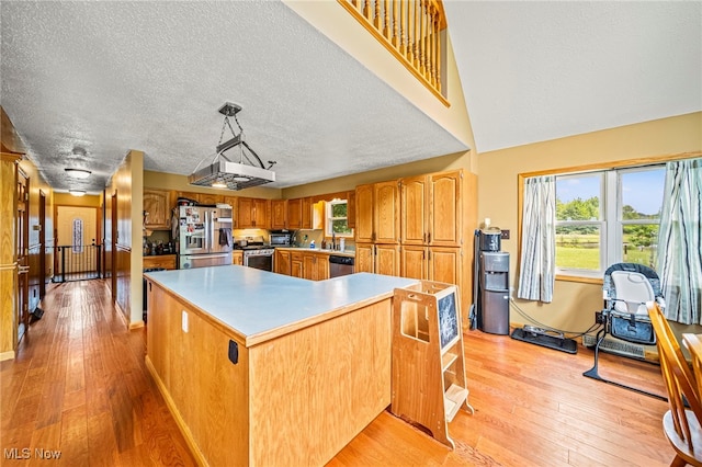 5050 Middle Rd, Conneaut, OH 44030 - kitchen with stainless steel appliances, light wood-style flooring, a kitchen island, brown cabinetry, and light countertops