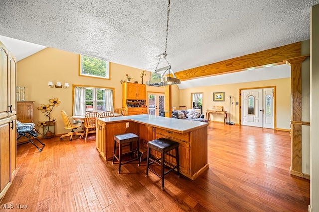 5050 Middle Rd, Conneaut, OH 44030 - kitchen with a textured ceiling, a center island, light wood-type flooring, vaulted ceiling, and decorative light fixtures