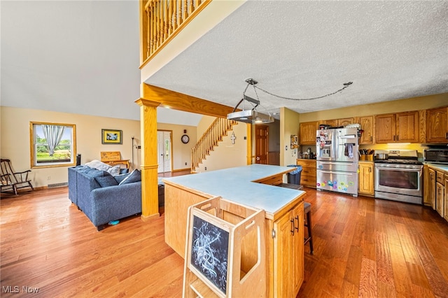 5050 Middle Rd, Conneaut, OH 44030 - kitchen featuring stainless steel appliances, light wood-style flooring, brown cabinetry, open floor plan, and a kitchen island