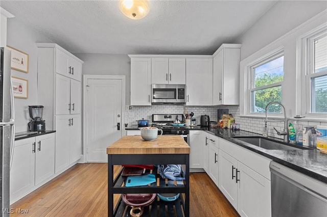 14317-14319 Bayes Ave, Lakewood, OH 44107 - kitchen with appliances with stainless steel finishes, light wood-style flooring, tasteful backsplash, and white cabinets