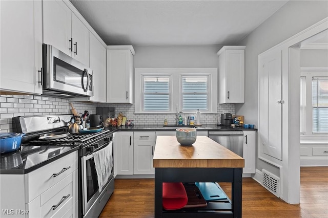 14317-14319 Bayes Ave, Lakewood, OH 44107 - kitchen with appliances with stainless steel finishes, tasteful backsplash, white cabinets, and dark wood-style flooring