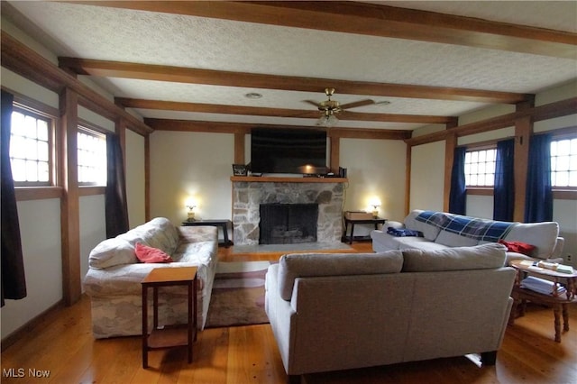 45 Mechanic St, Berlin Heights, OH 44814 - living area with beam ceiling, light wood finished floors, a fireplace, ceiling fan, and a textured ceiling