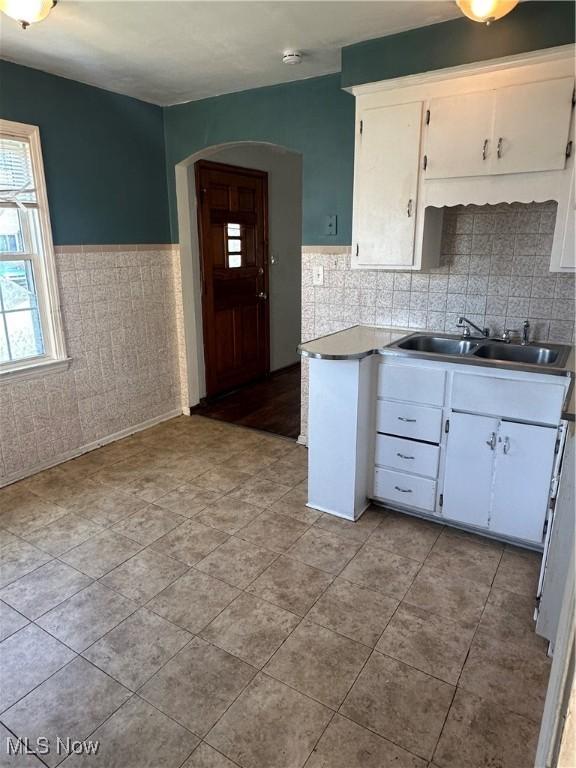5252 W 45th St, Parma, OH 44134 - kitchen with white cabinets, arched walkways, wainscoting, light tile patterned floors, and tile walls