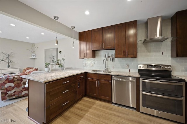 629-37 Fairington Oval, Aurora, OH 44202 - kitchen featuring appliances with stainless steel finishes, wall chimney range hood, tasteful backsplash, light wood-style flooring, and recessed lighting