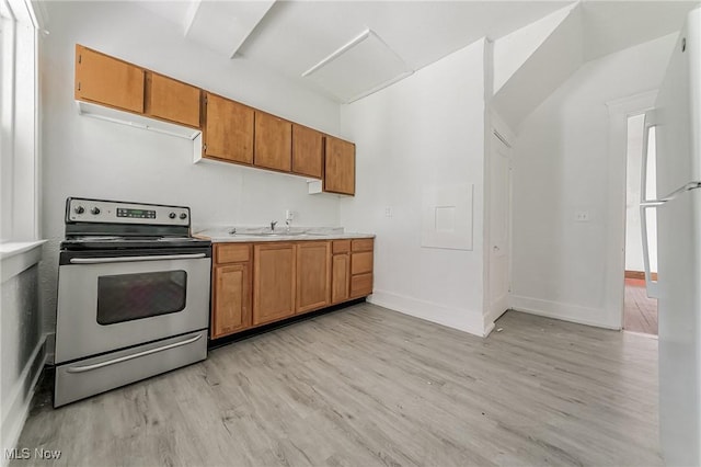 1150 W 5th St, Lorain, OH 44052 - kitchen featuring electric stove, light wood finished floors, brown cabinets, light countertops, and freestanding refrigerator