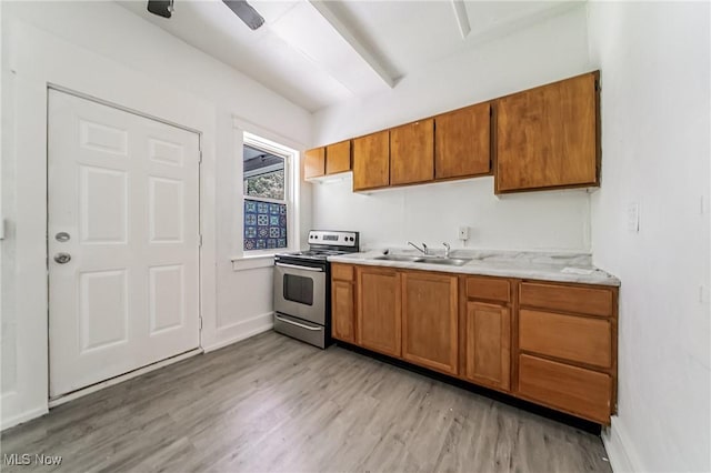 1150 W 5th St, Lorain, OH 44052 - kitchen featuring stainless steel electric stove, light wood-style floors, brown cabinetry, and light countertops