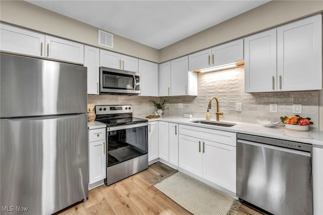 4499 Camellia Ln, North Olmsted, OH 44070 - kitchen featuring stainless steel appliances, light countertops, light wood-style floors, tasteful backsplash, and white cabinets