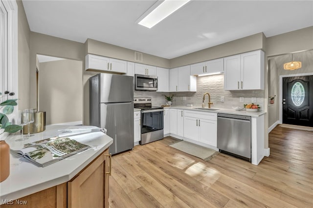 4499 Camellia Ln, North Olmsted, OH 44070 - kitchen with appliances with stainless steel finishes, light countertops, light wood-style floors, and white cabinets