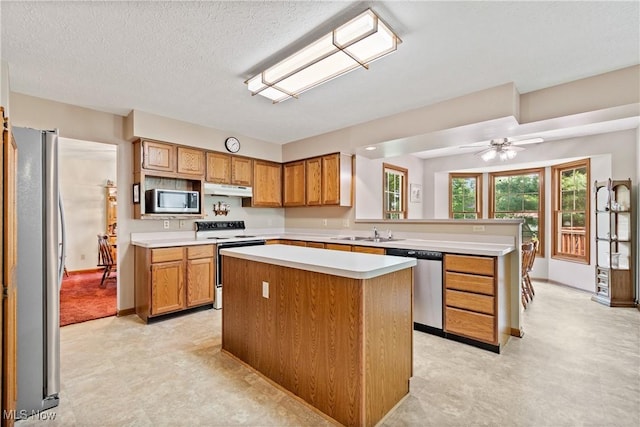 525 Bishop Pl, Berea, OH 44017 - kitchen featuring appliances with stainless steel finishes, under cabinet range hood, light countertops, brown cabinets, and a peninsula