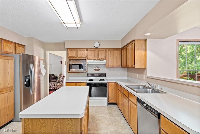 525 Bishop Pl, Berea, OH 44017 - kitchen featuring stainless steel appliances, under cabinet range hood, light countertops, a center island, and brown cabinets