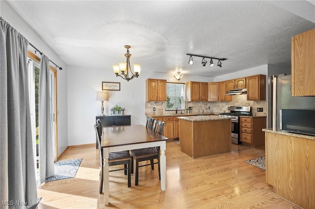 1036 Larkens Way, Medina, OH 44256 - kitchen with gas range, under cabinet range hood, a kitchen island, light wood-style floors, and decorative backsplash