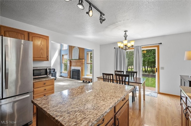 1036 Larkens Way, Medina, OH 44256 - kitchen with appliances with stainless steel finishes, a chandelier, a fireplace, light wood-type flooring, and a textured ceiling