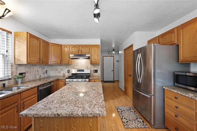 1036 Larkens Way, Medina, OH 44256 - kitchen featuring appliances with stainless steel finishes, under cabinet range hood, a textured ceiling, light wood-style flooring, and light stone countertops