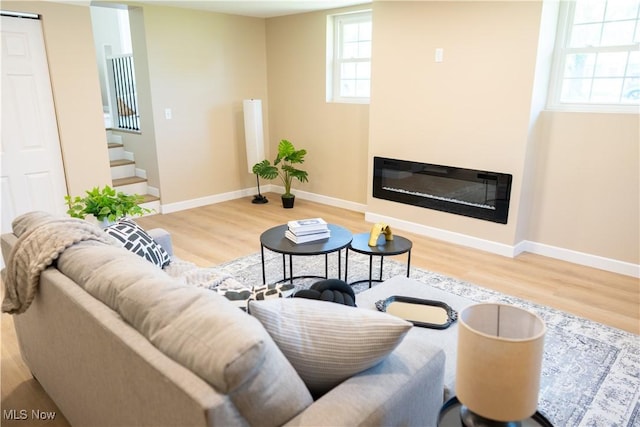5699 Colgate Ave, Austintown, OH 44515 - living area with wood finished floors, healthy amount of natural light, a glass covered fireplace, and stairs