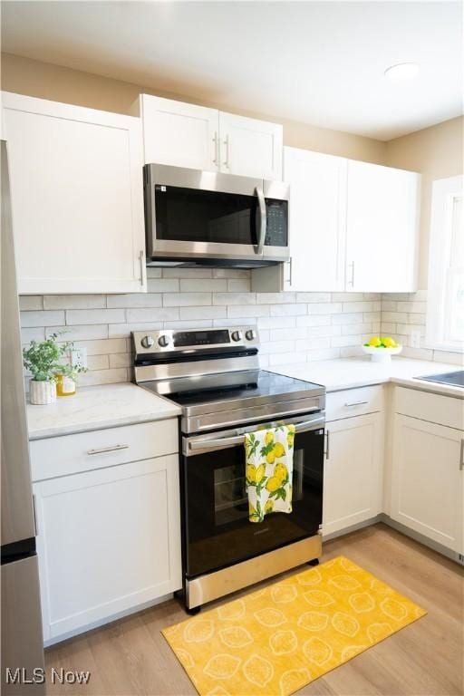 5699 Colgate Ave, Austintown, OH 44515 - kitchen with stainless steel appliances, light countertops, white cabinets, light wood-style floors, and tasteful backsplash
