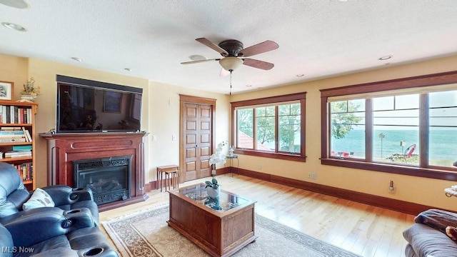 1431 Cedar Point Rd, Sandusky, OH 44870 - living room featuring light wood-type flooring, a fireplace with raised hearth, ceiling fan, and a textured ceiling