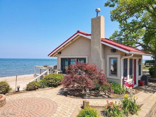 1431 Cedar Point Rd, Sandusky, OH 44870 - back of house featuring a water view, stucco siding, a chimney, and a patio