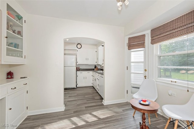 2215 S Belvoir Blvd, University Heights, OH 44118 - kitchen featuring freestanding refrigerator, arched walkways, white cabinets, light wood-style floors, and glass insert cabinets