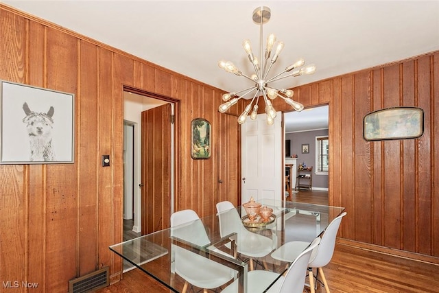 2215 S Belvoir Blvd, University Heights, OH 44118 - dining space with a chandelier, wood finished floors, wooden walls, and crown molding