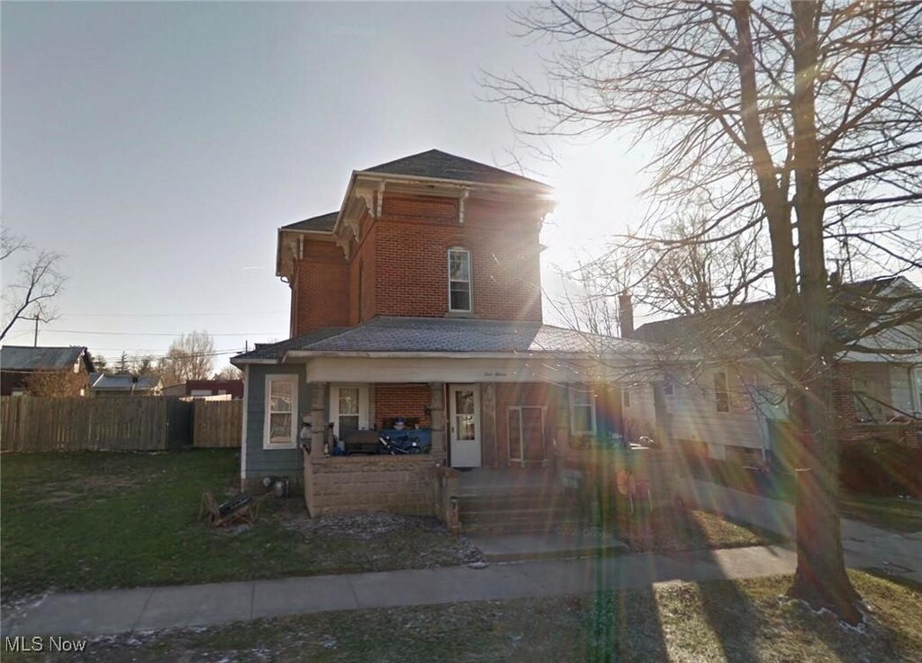 411 E Lima St, Forest, OH 45843 - italianate-style house featuring covered porch, brick siding, and a chimney