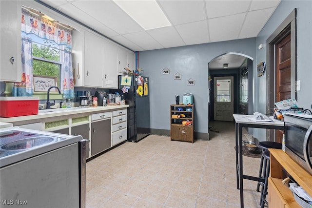 415 N Columbus St, Crestline, OH 44827 - kitchen with freestanding refrigerator, a drop ceiling, white electric range oven, arched walkways, and light countertops