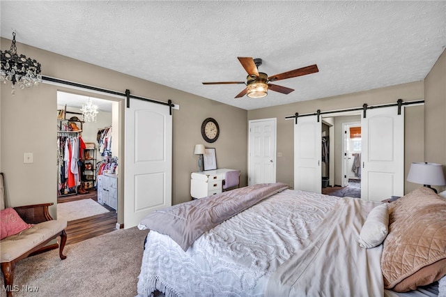 12208 State Route 113, Wakeman, OH 44889 - bedroom featuring a barn door, a walk in closet, a textured ceiling, and a ceiling fan