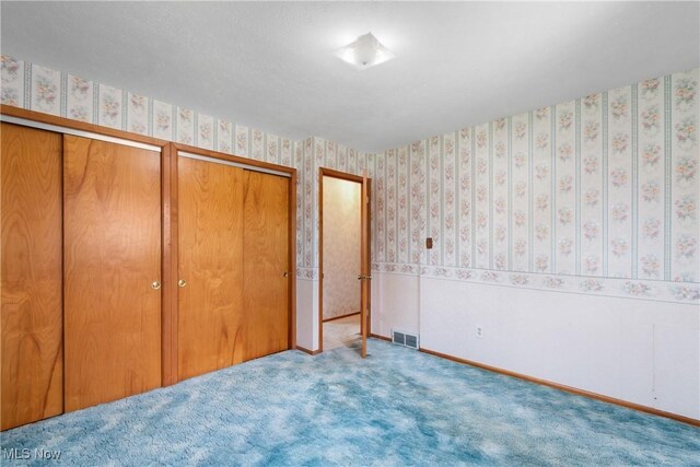 4899 Autumn Ln, Brooklyn, OH 44144 - unfurnished bedroom with wallpapered walls, two closets, and carpet flooring