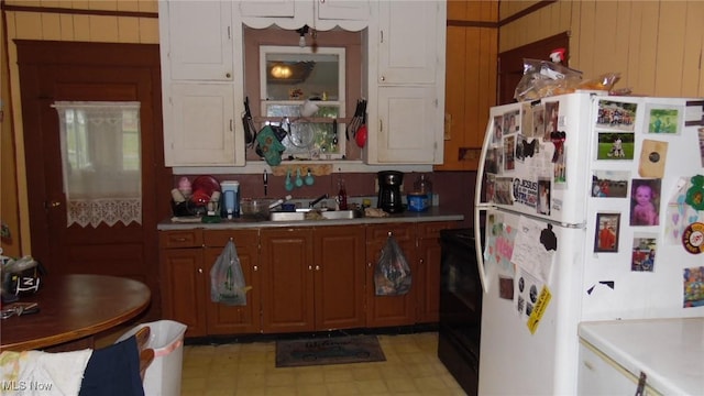 430 S 3rd St, Coshocton, OH 43812 - kitchen with freestanding refrigerator, range, light countertops, brown cabinetry, and wooden walls