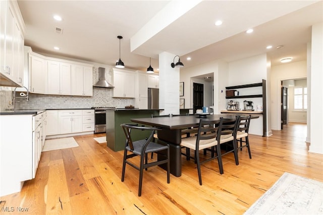 1906 W 47th St, Cleveland, OH 44102 - kitchen featuring wall chimney range hood, stainless steel appliances, light wood-style flooring, dark countertops, and recessed lighting