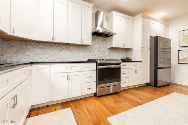 1906 W 47th St, Cleveland, OH 44102 - kitchen with stainless steel appliances, wall chimney range hood, light wood finished floors, white cabinetry, and recessed lighting