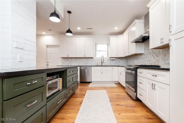 1906 W 47th St, Cleveland, OH 44102 - kitchen with stainless steel appliances, wall chimney exhaust hood, white cabinetry, dark countertops, and decorative backsplash