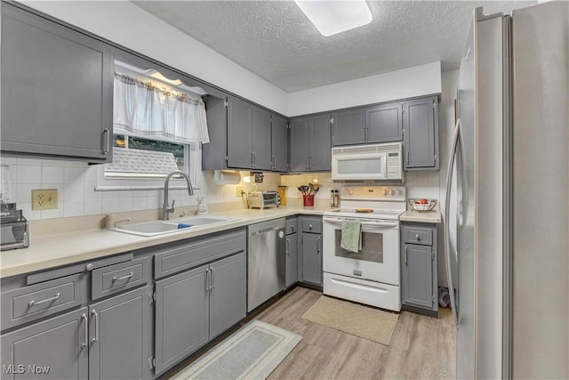 4090 Ridgeview Rd, Cleveland, OH 44144 - kitchen featuring stainless steel appliances, gray cabinets, a textured ceiling, light wood-style floors, and decorative backsplash