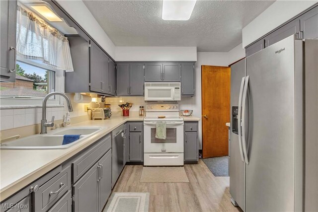 4090 Ridgeview Rd, Cleveland, OH 44144 - kitchen with stainless steel appliances, gray cabinets, a textured ceiling, light wood-style flooring, and decorative backsplash