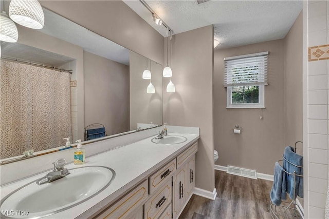 4090 Ridgeview Rd, Cleveland, OH 44144 - bathroom with double vanity, wood finished floors, a textured ceiling, and curtained shower