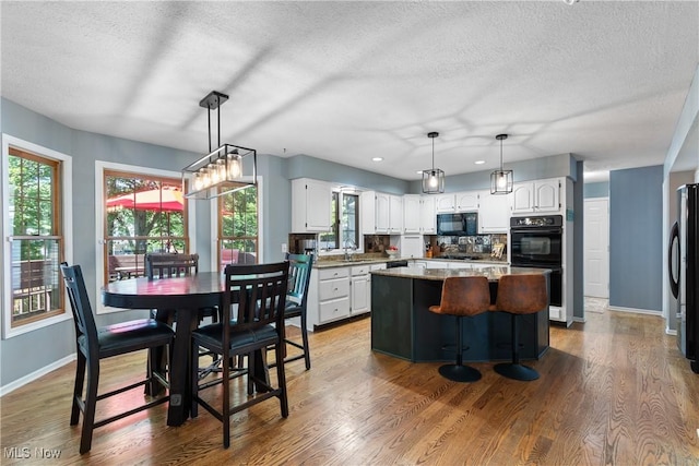 3049 Deercrest Path, Stow, OH 44224 - kitchen featuring black appliances, a kitchen island, white cabinets, a textured ceiling, and wood finished floors