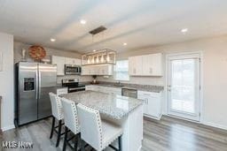 105 Vesper Cir, Lodi, OH 44254 - kitchen featuring stainless steel appliances, white cabinetry, a kitchen breakfast bar, dark wood finished floors, and a kitchen island
