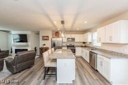 105 Vesper Cir, Lodi, OH 44254 - kitchen featuring appliances with stainless steel finishes, open floor plan, white cabinets, and a kitchen breakfast bar