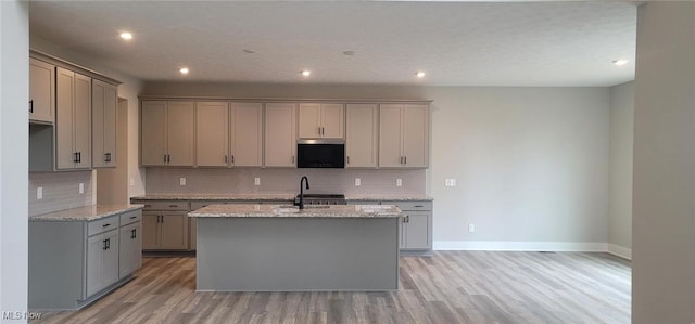 9125 Ledge View Ter, Broadview Heights, OH 44147 - kitchen featuring stainless steel microwave, gray cabinets, light wood-style floors, backsplash, and a kitchen island with sink