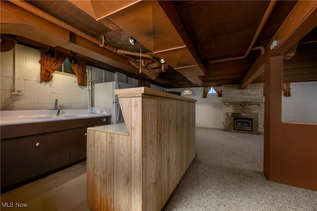 731 Hemlock St NW, Massillon, OH 44647 - finished below grade area with a fireplace, light carpet, freestanding refrigerator, and concrete block wall
