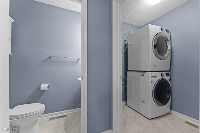 184 Creekledge Ln, Copley, OH 44321 - washroom with stacked washer and clothes dryer, a textured ceiling, and marble look tile flooring