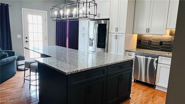 116 Ledgestone Ct, Berea, OH 44017 - kitchen with stainless steel appliances, light wood-style flooring, backsplash, a kitchen island, and white cabinets