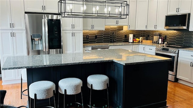 116 Ledgestone Ct, Berea, OH 44017 - kitchen with stainless steel appliances, white cabinets, backsplash, a kitchen island, and a breakfast bar area