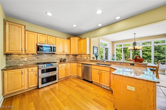 11275 Beechnut Ln, Chardon, OH 44024 - kitchen featuring stainless steel appliances, a peninsula, dark stone counters, tasteful backsplash, and a chandelier