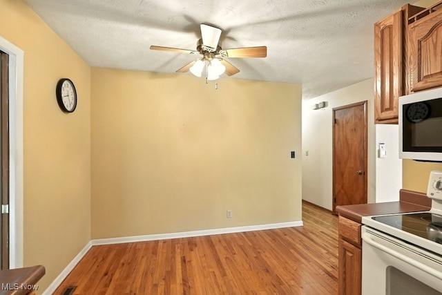 3692 Orchard St, Mogadore, OH 44260 - kitchen featuring white appliances, light wood-style flooring, ceiling fan, brown cabinets, and a textured ceiling