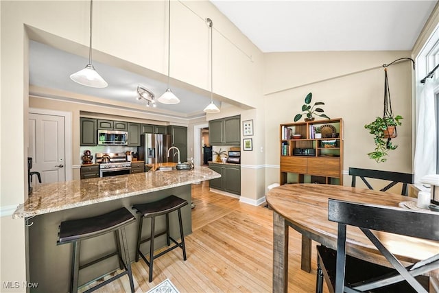 6735 Wakefield Rd, Hiram, OH 44234 - kitchen with appliances with stainless steel finishes, lofted ceiling, a kitchen breakfast bar, light wood-style flooring, and light stone counters