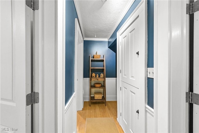 6735 Wakefield Rd, Hiram, OH 44234 - hall with light wood-type flooring, a textured ceiling, crown molding, and a wainscoted wall