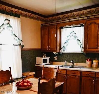 134 E Summit St, Alliance, OH 44601 - kitchen featuring white microwave, light countertops, and brown cabinets